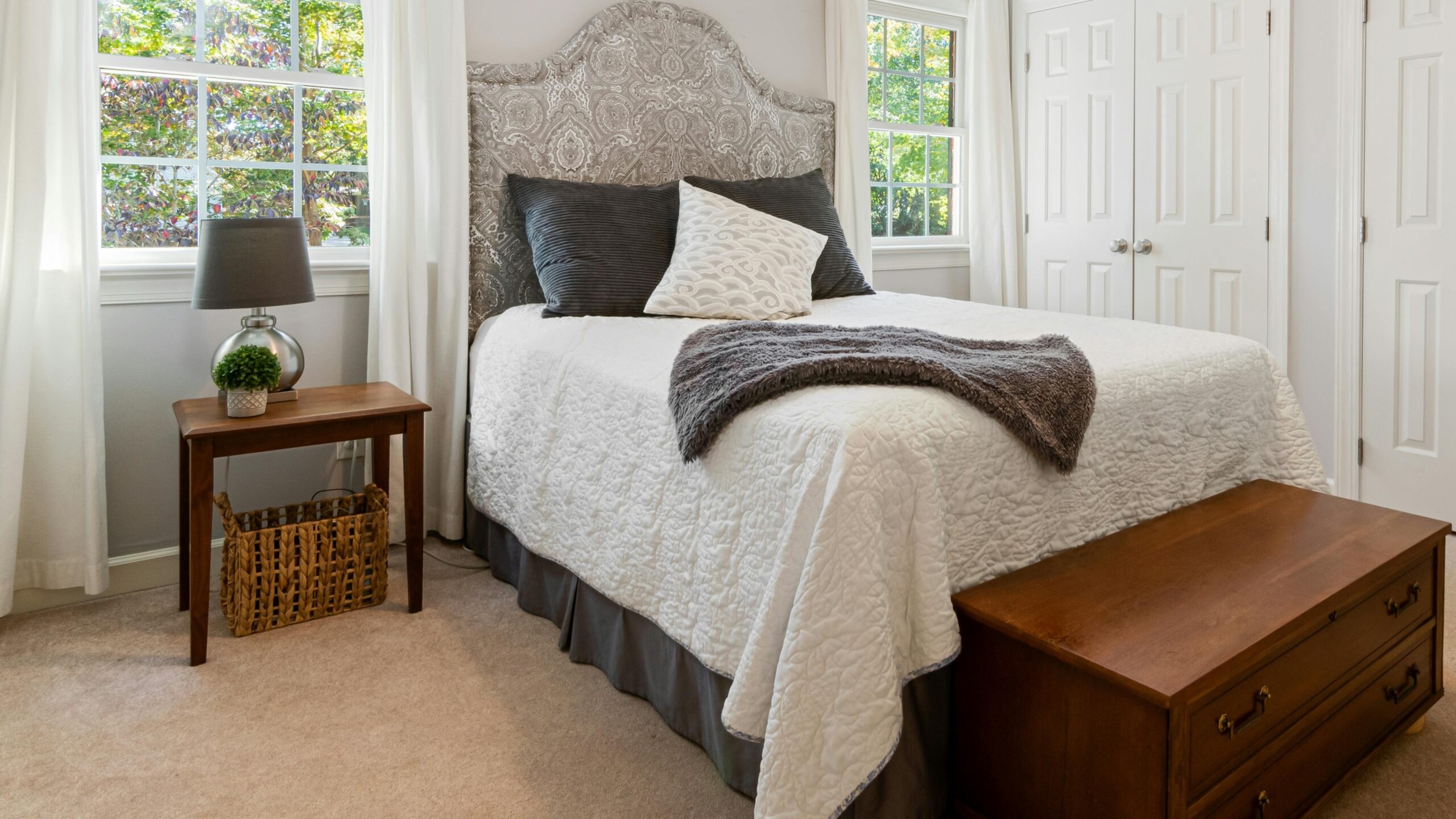 Eclectic primary bedroom features neutral carpet.